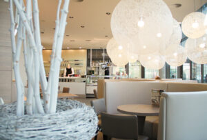 Eiscafé LaLuna Essen, Sitzplatz mit dekorativen Elementen, mehrere weiße Lampenschirme in Form einer Kugel hängen in unterschiedlichen Größen von der Decke.